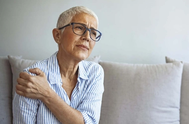 A woman holding her shoulder, in pain.