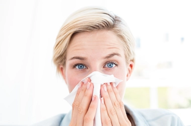 A woman holding a tissue up to her face.