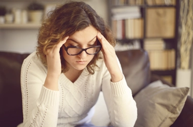 A woman holding the sides of her head.