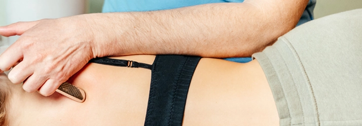 A person receiving Guasha on their shoulder.