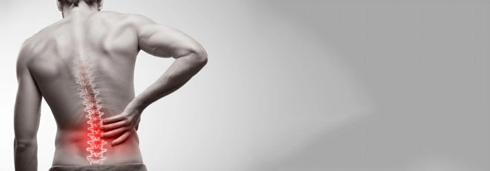 A man holding his lower back. His back is highlighted red.