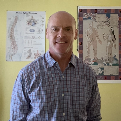 Douglas Paige smiling while wearing a striped button-up shirt.